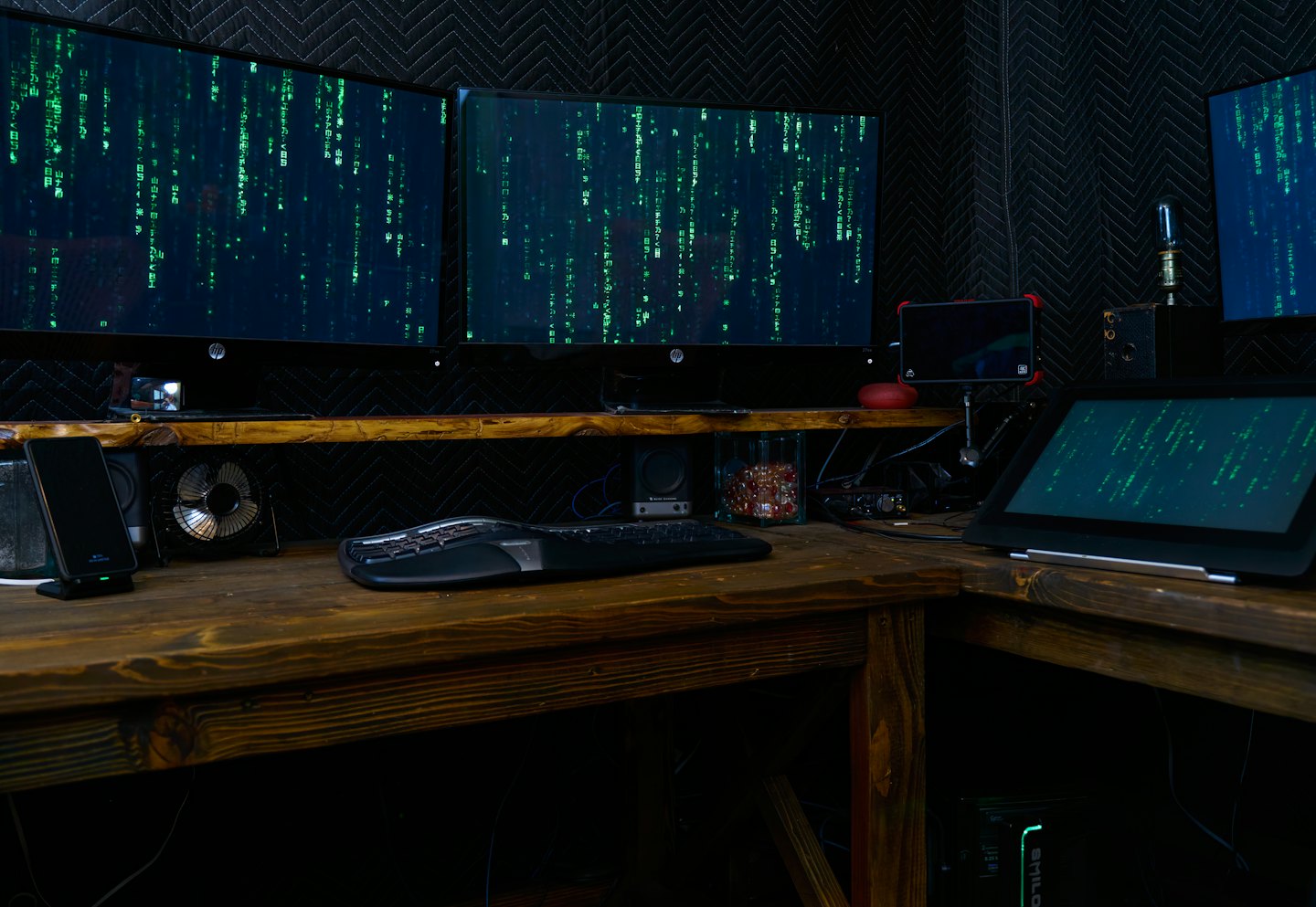 Plusieurs écrans d'ordinateur affichant du code vert dans une pièce sombre.