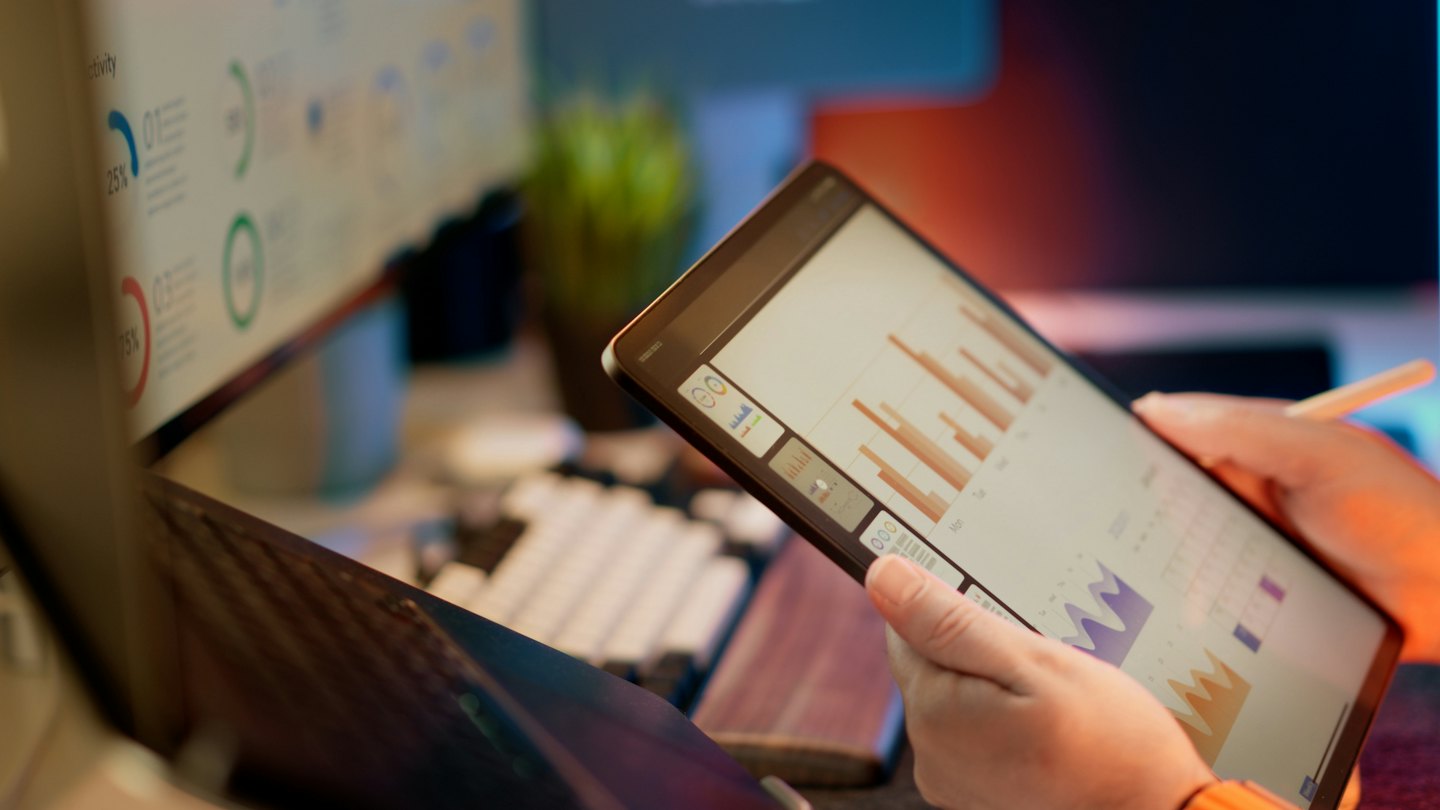Personne analysant des graphiques d'entreprise sur une tablette à un bureau.